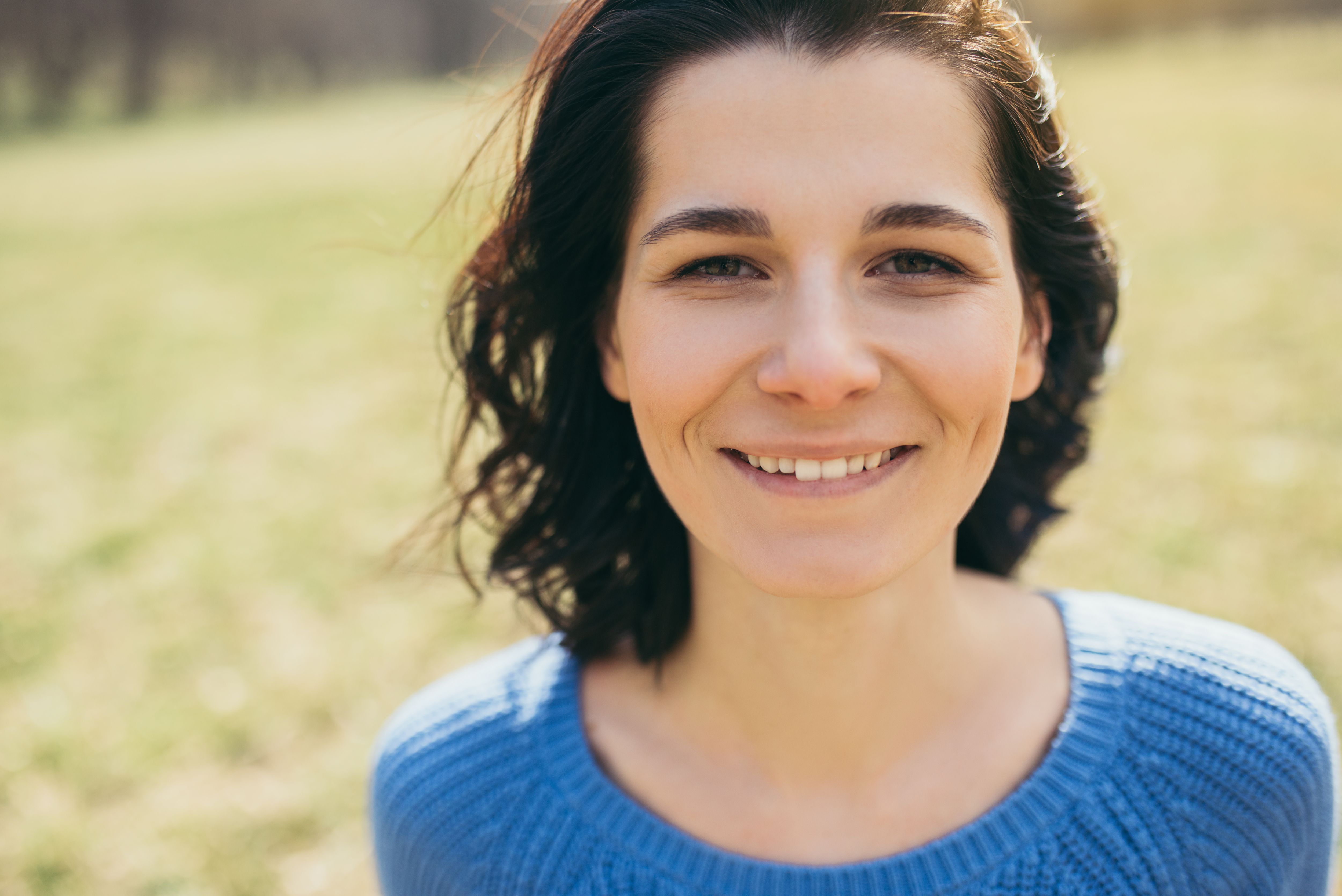Woman smiling, standing outdoors.